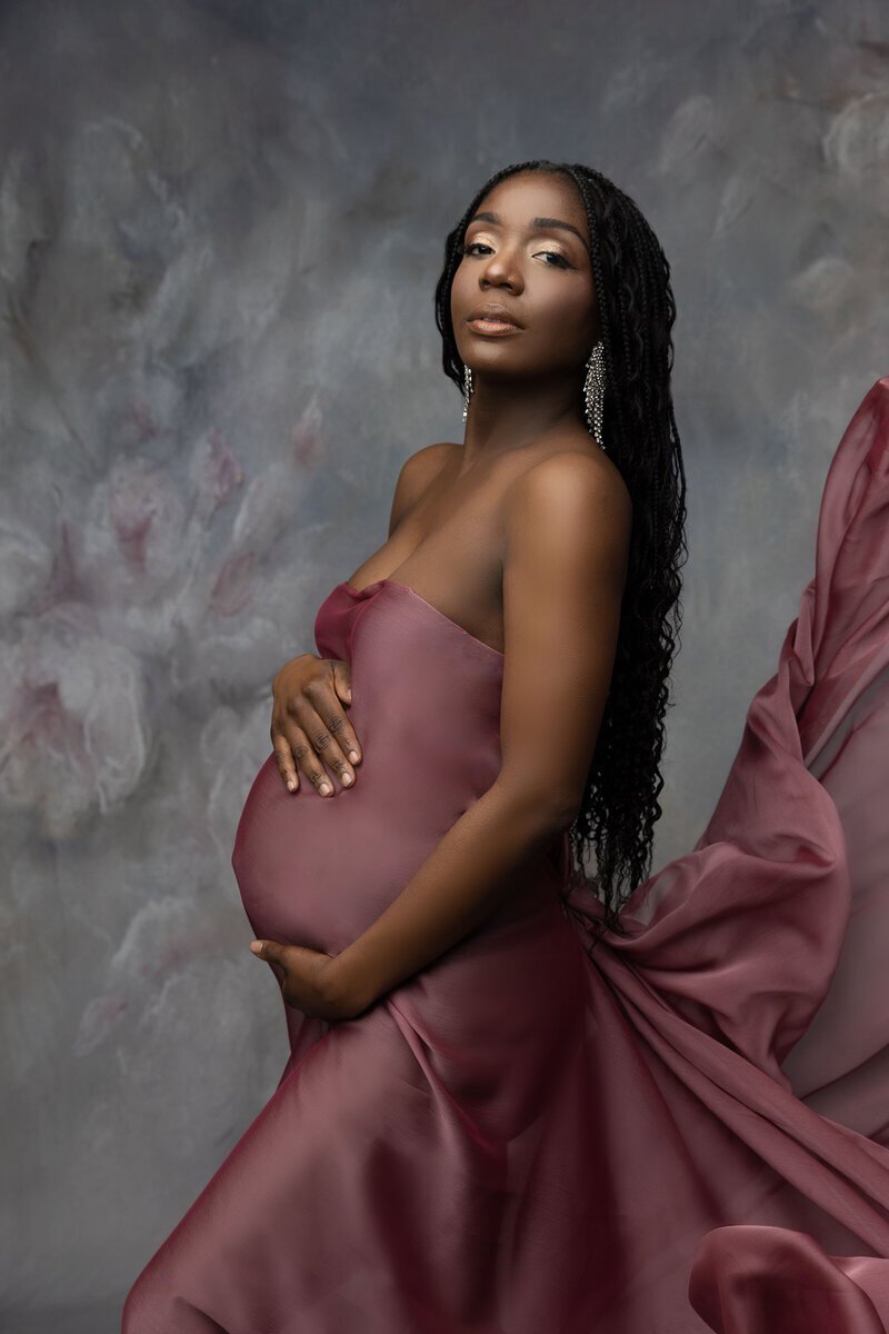 Pregnant woman holding baby bump wearing pink, taken by maternity photographer new jersey