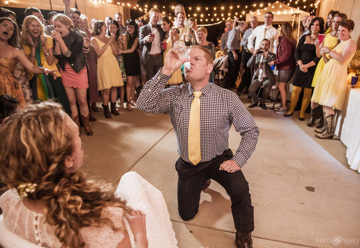 Groom is smirnoff iced by his bride during garter toss at Estes park YMCA of the Rockies wedding in Colorado