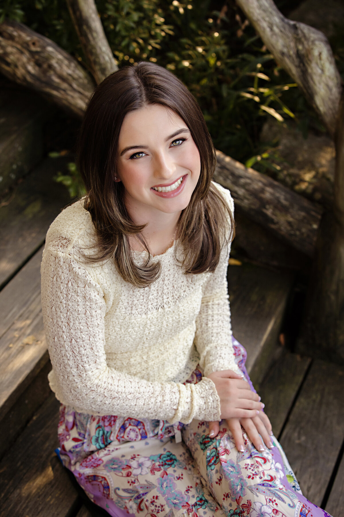 High school senior in cream lace top and long skirt posing on outdoor steps with warm autumn tones