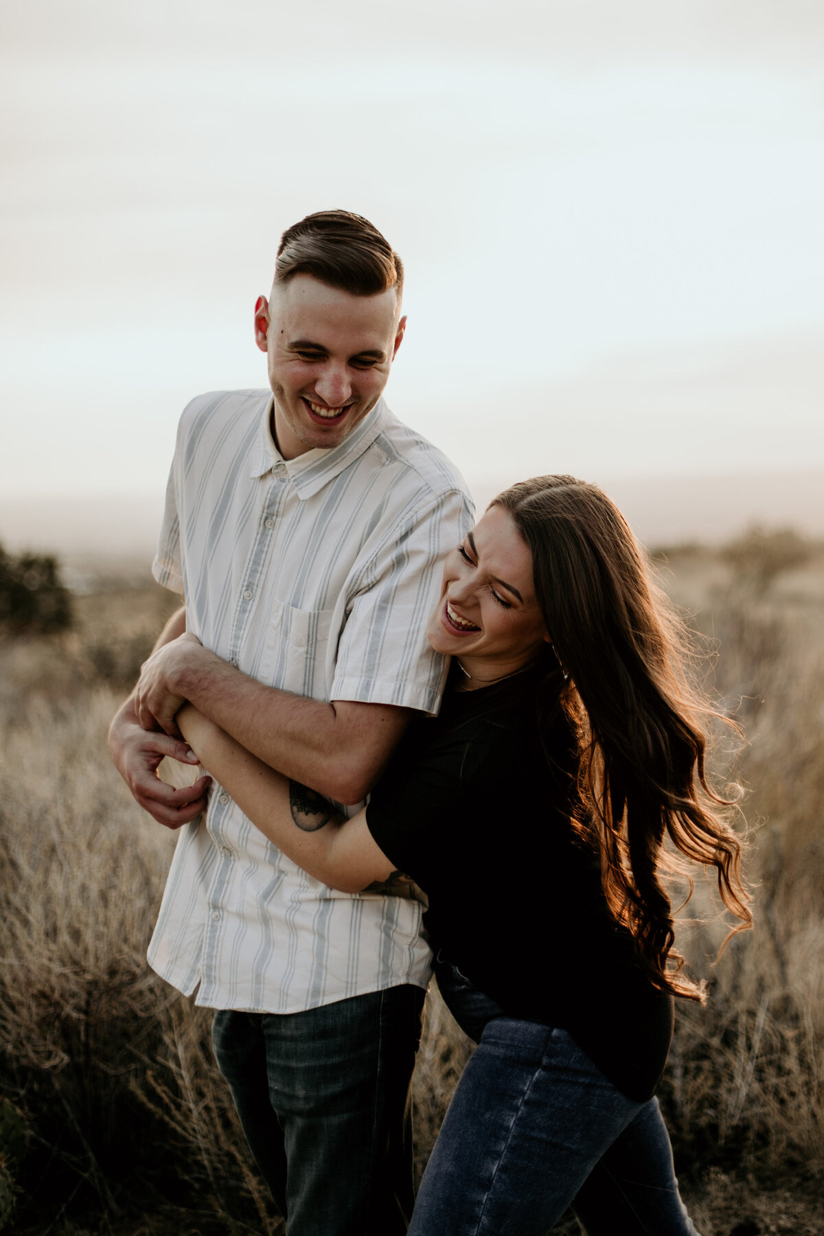 engaged couple laughing and holding each other in the desert