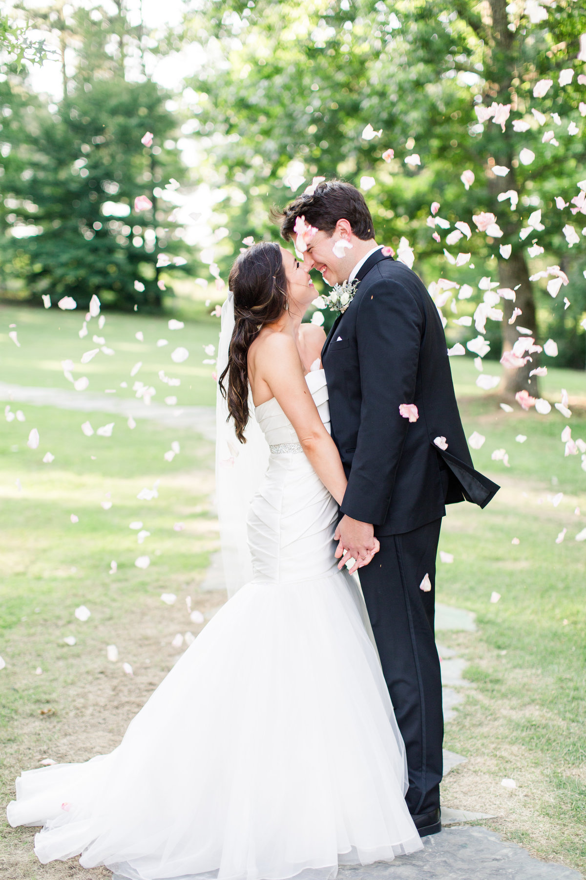 Bride and groom kissing under rose petals at The Barn at Shady Lane in Birmingham, Alabama