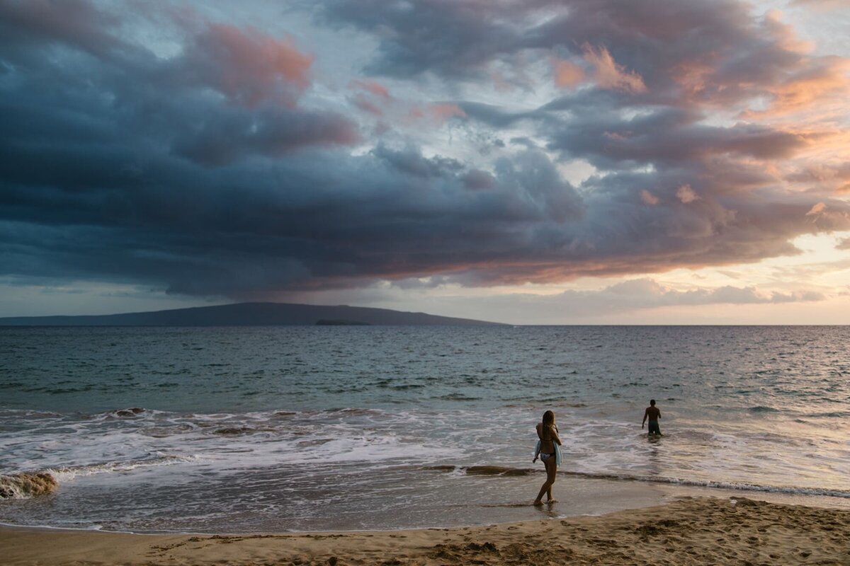 Two people play on the beach with a beautiful sunset in Maui