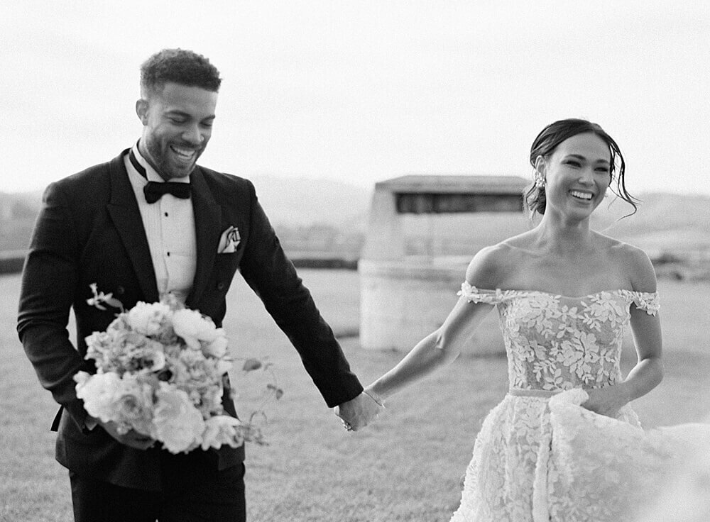 bride and groom run across grass in black and white at Cal-a-vie | Jacqueline Benét