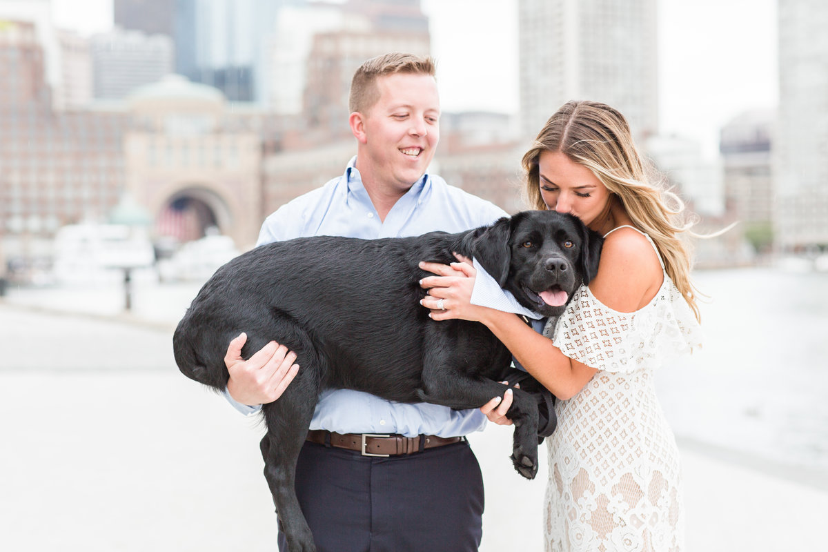 Couple kissing their black lab in the Boston Seaport