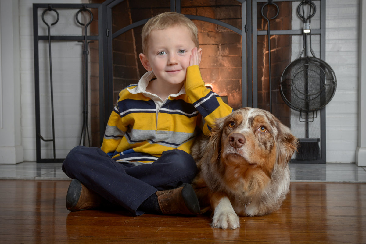 A boy and his dog in front of a fireplace during a family portrait session
