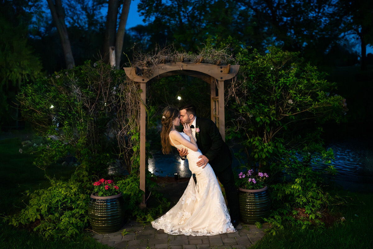 Bride and groom kiss in a garden at night in Eagan, Minnesota.
