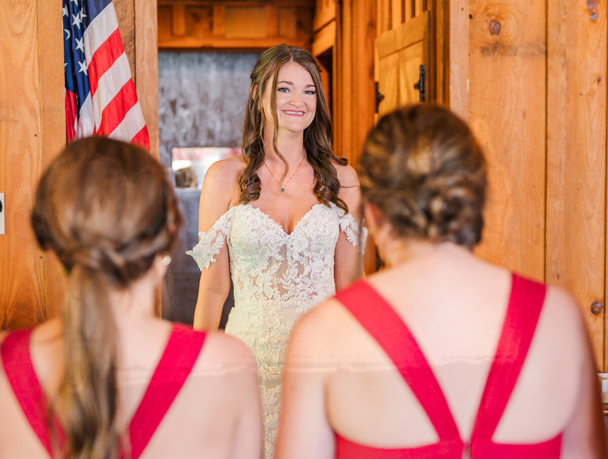 A bride having her first look with her bridesmaids as they all  have eyes filled with tears at the Angus Barn by JoLynn Photography, a North Carolina wedding photographer