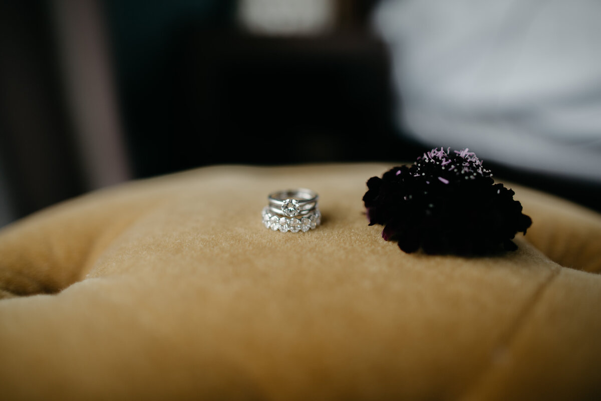Wedding rings sitting on ottoman next to flowers