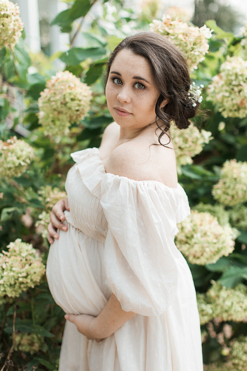 pregnant asian mom stands in front of hydrangeas