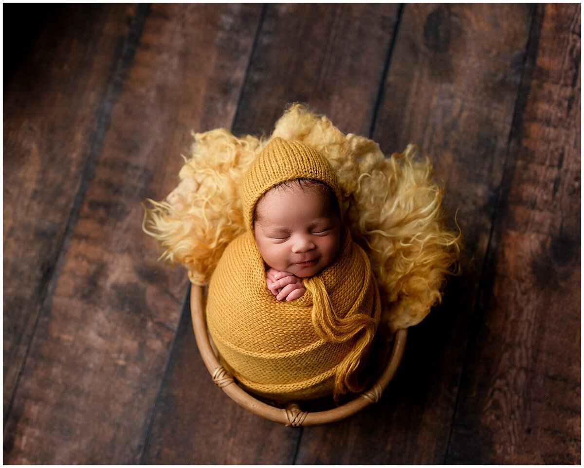 newborn boy wrapped in mustard wrap in basket with fur