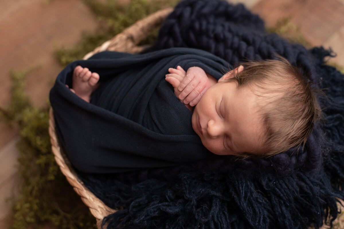 Newborn boy wrapped in navy blue