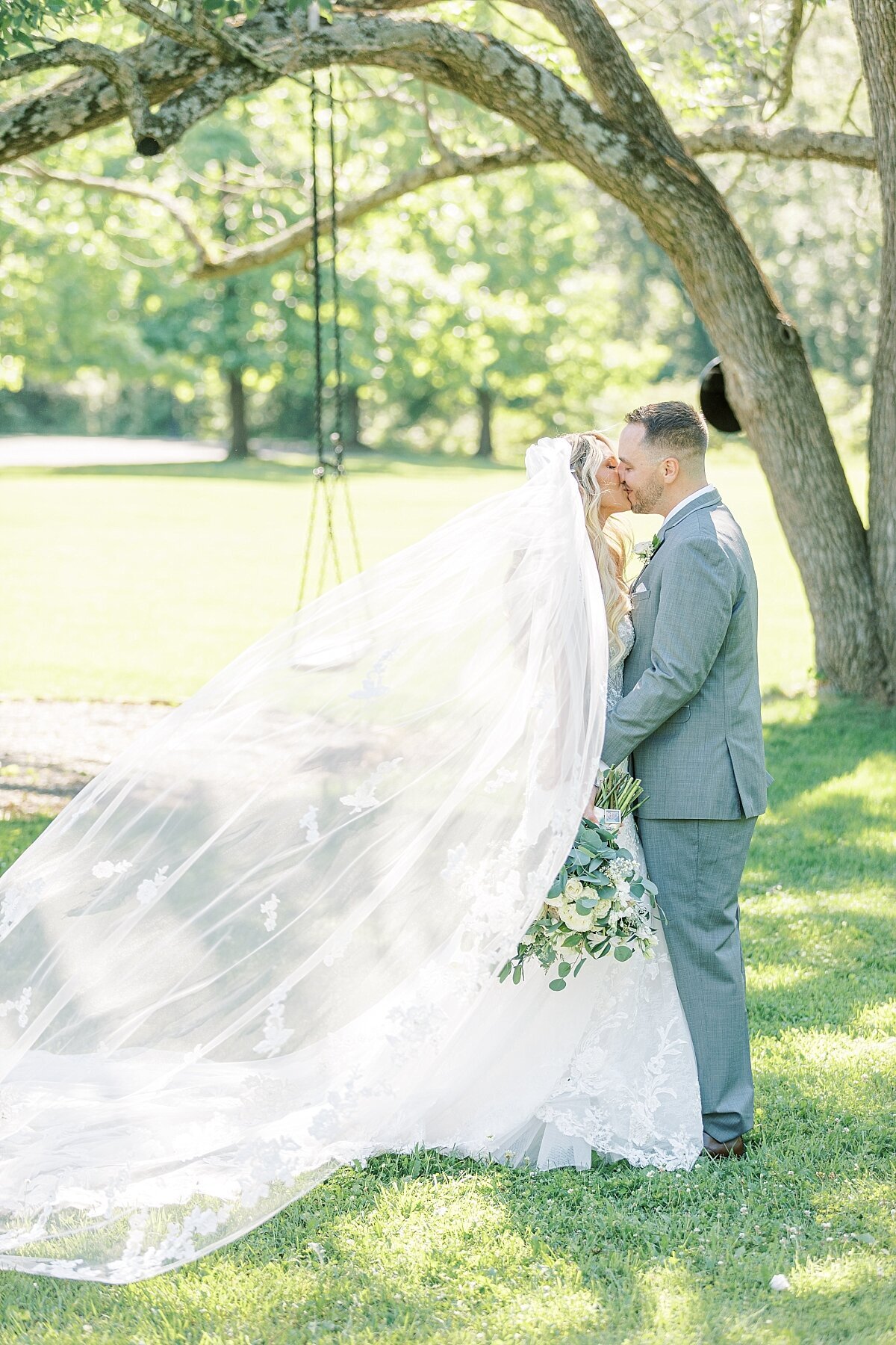 bride and groom kissing with veil flowing in wind