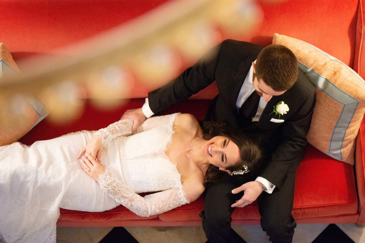 Top shot of bride and groom on the red softa at The Mansion at Oyster Bay