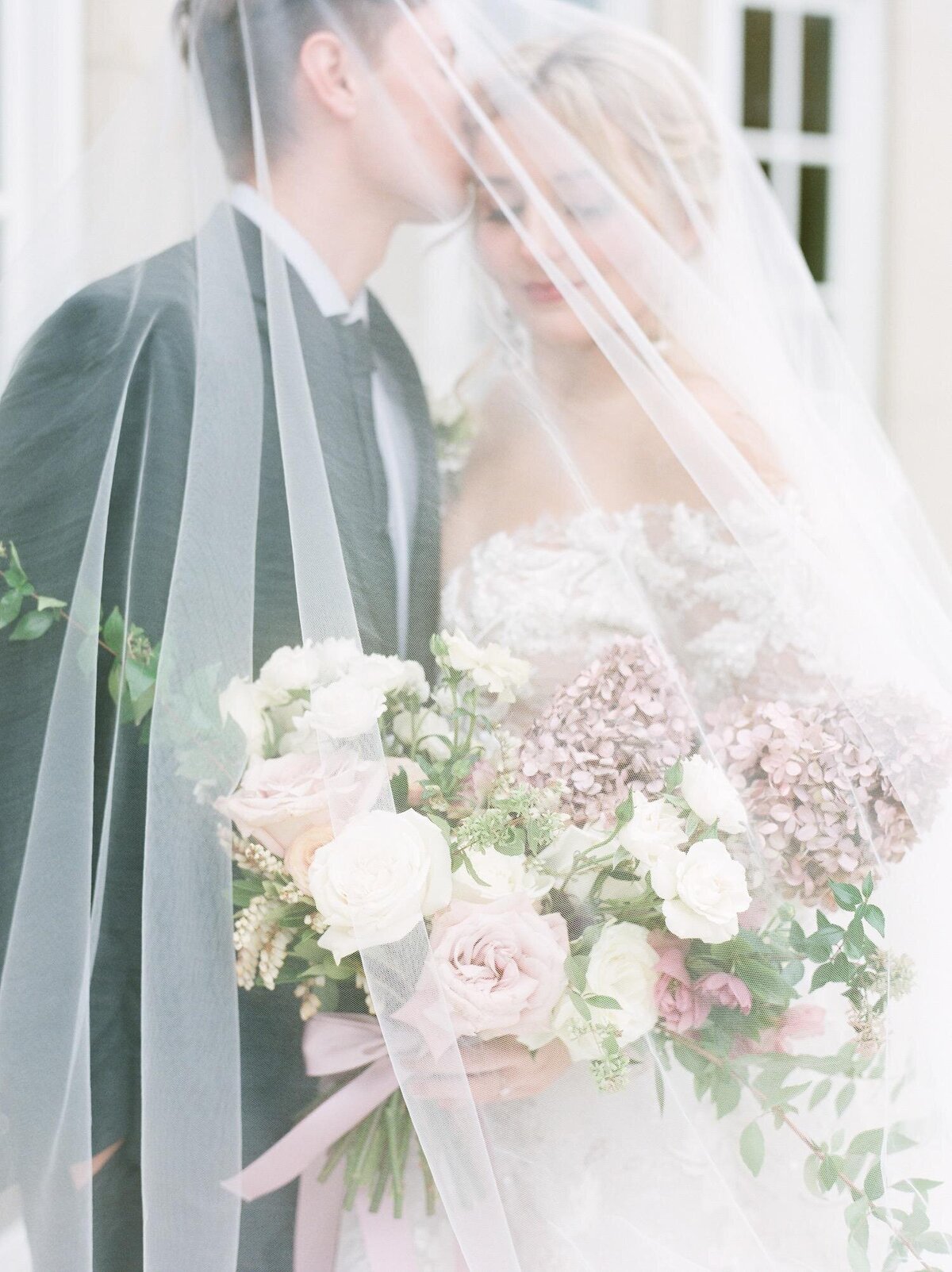 Bride-and-groom-under-veil-kissing-outside-The-Olana-in-Dallas-Texas.jpg