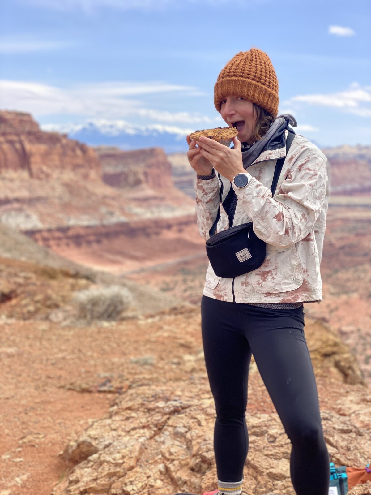 Aimee eats a fruit pie from Fruita at the top of a summit in Canyonlands National Park