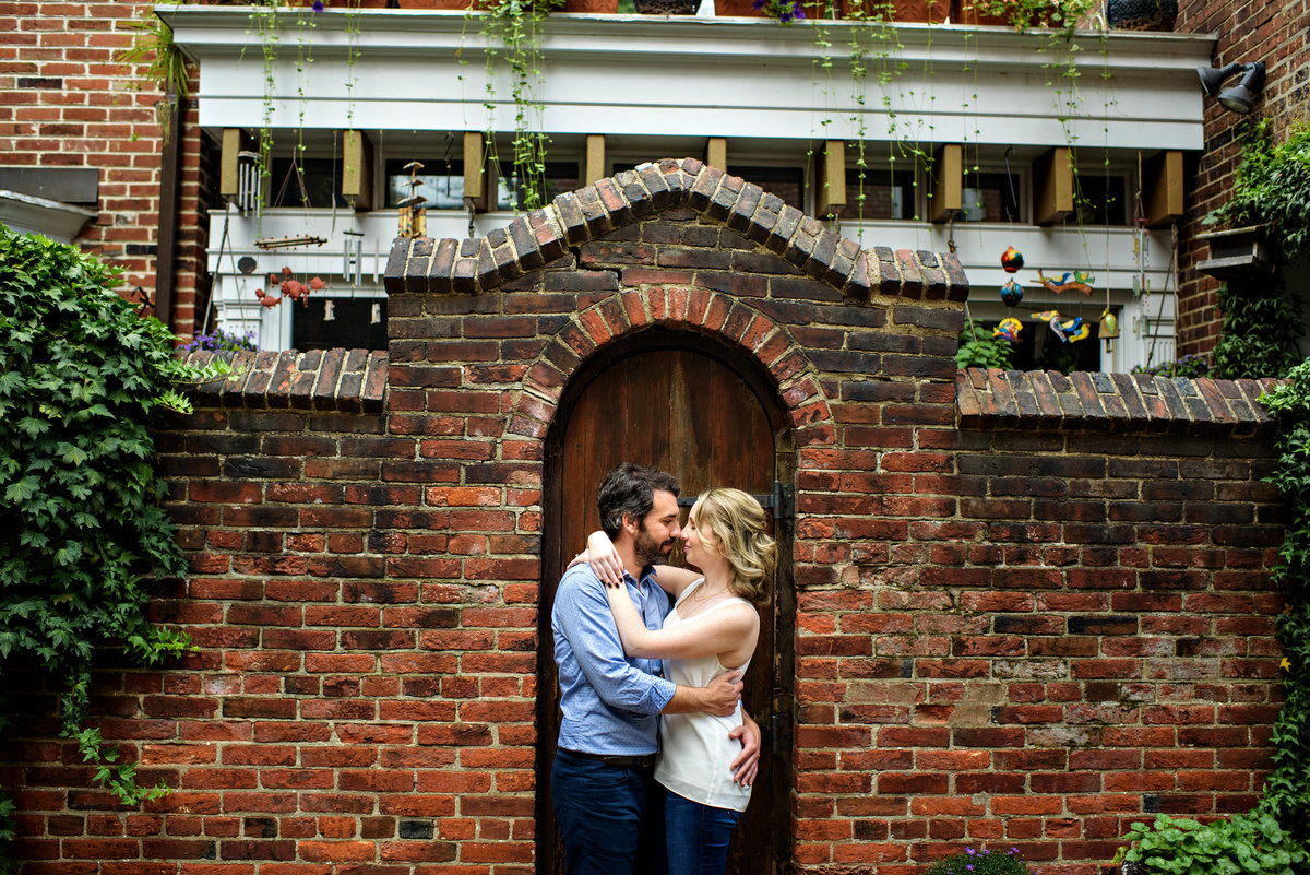 A couple in love with each other are framed in the doorway of a rowhome in center city philadelphia.