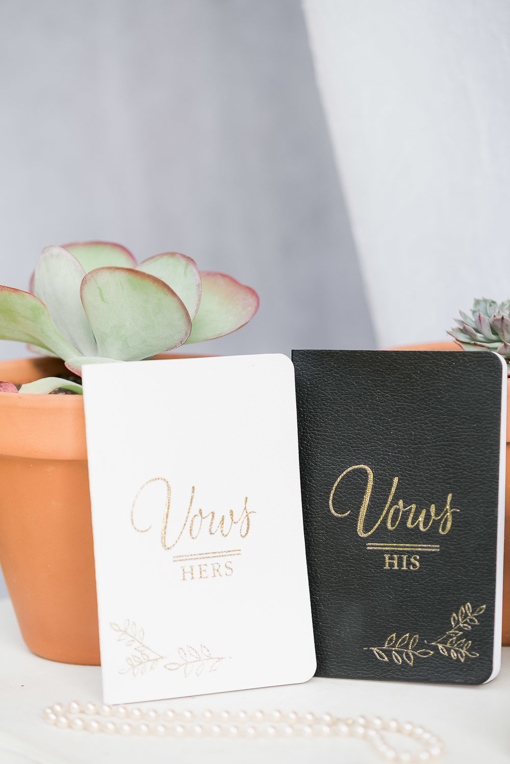 A white wedding vows book on the left and a black wedding vows book on the right
