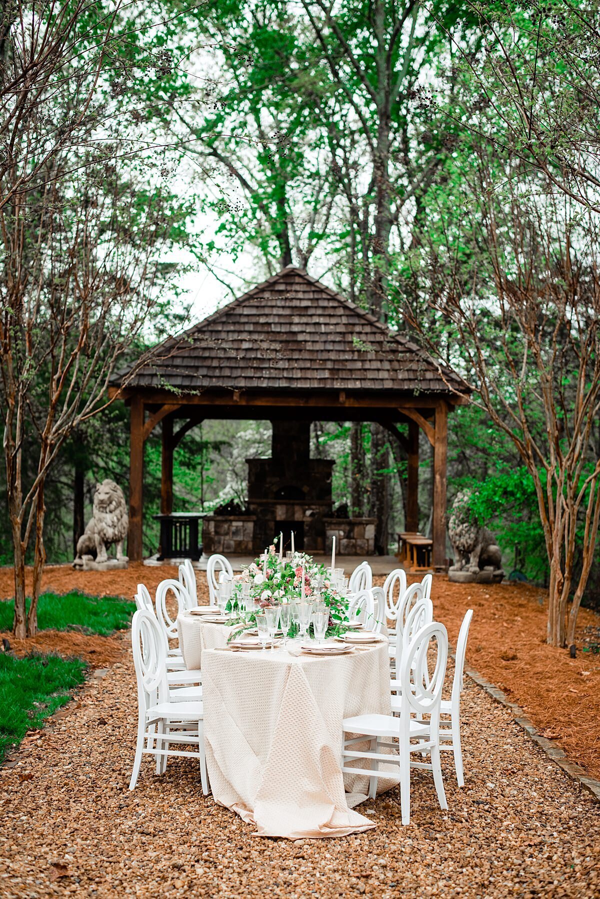 Outdoor head table with white chairs, ivory draping a s-shaped centerpiece