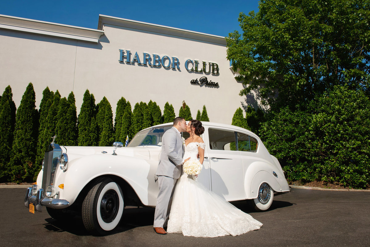 Bride and groom outside the sign of Harbor Club at Prime