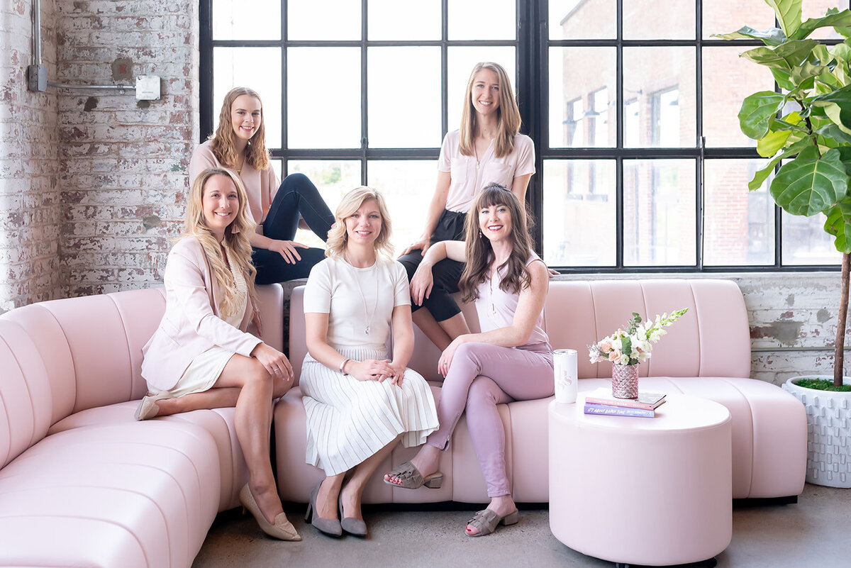 Her Story of Success team sitting on pink couch