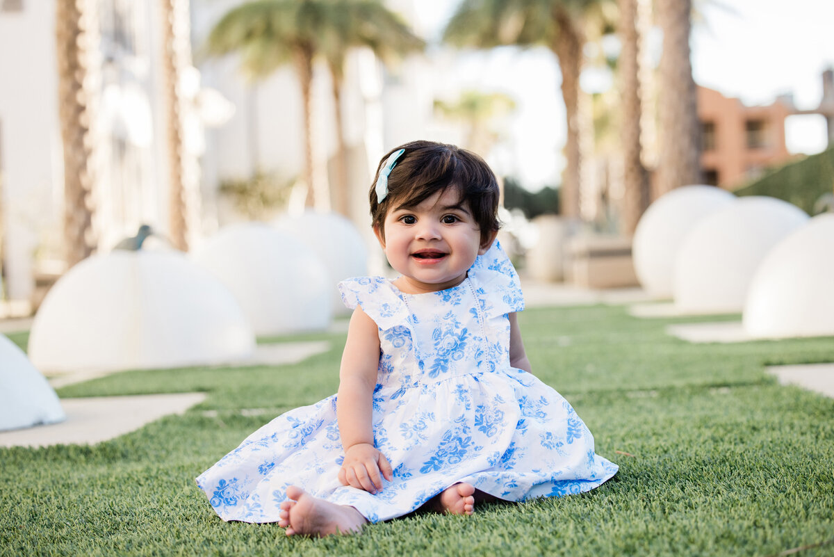 A small baby sitting in a grassy area