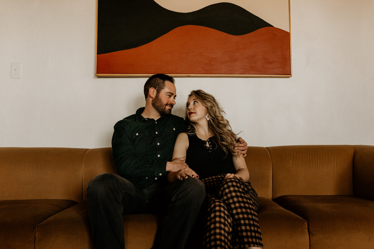 engaged couple sitting on a retro couch together