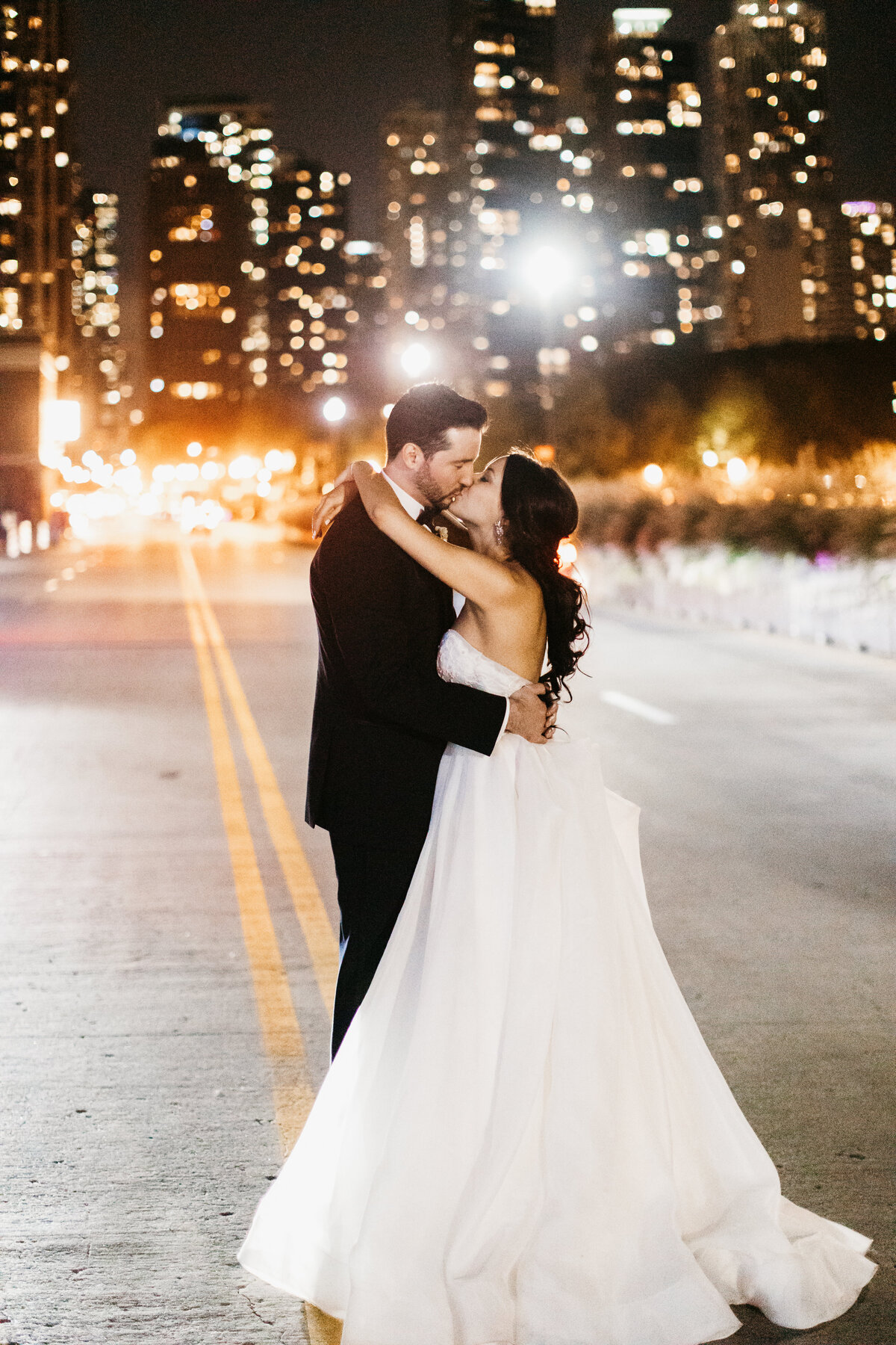 bride and groom kissing in the street under city lights in Chicago