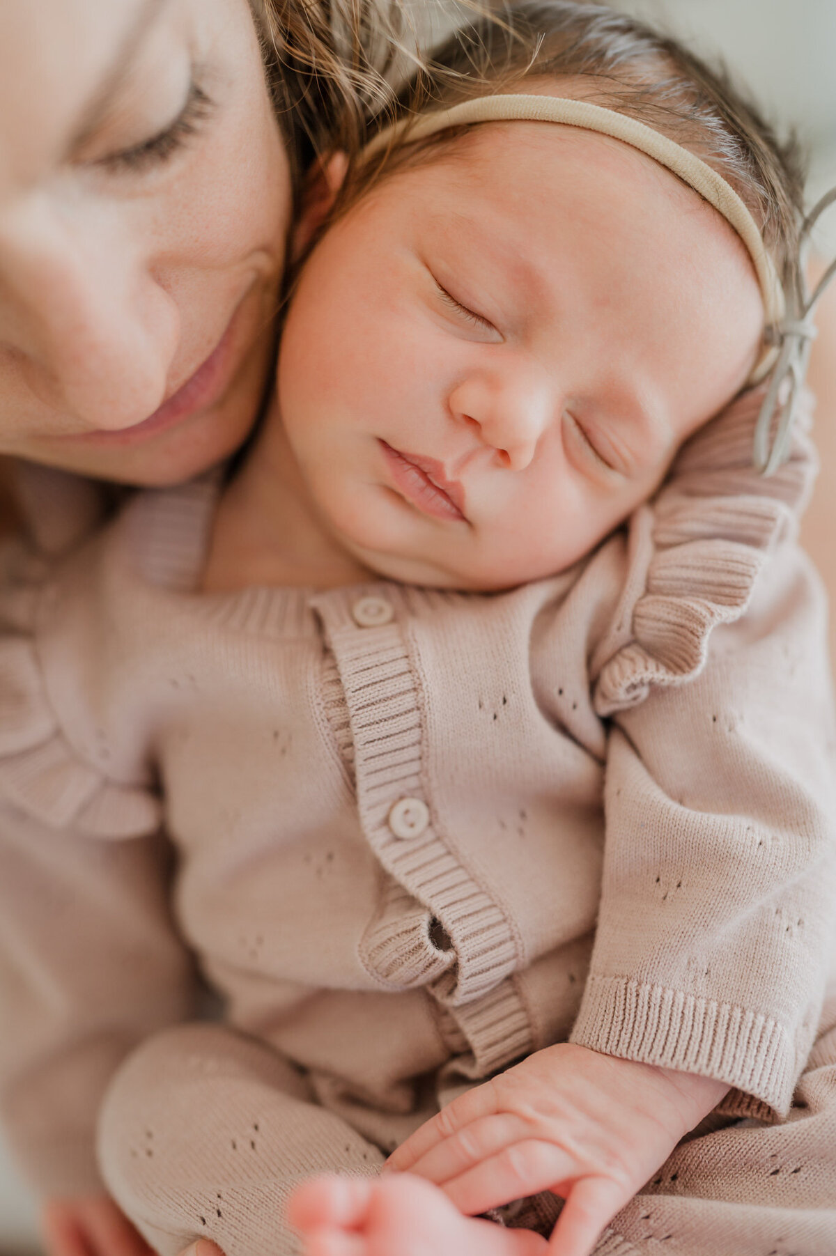 Mom nuzzles sleeping baby girl. Close up photo by newborn photographer Cassy Golden.