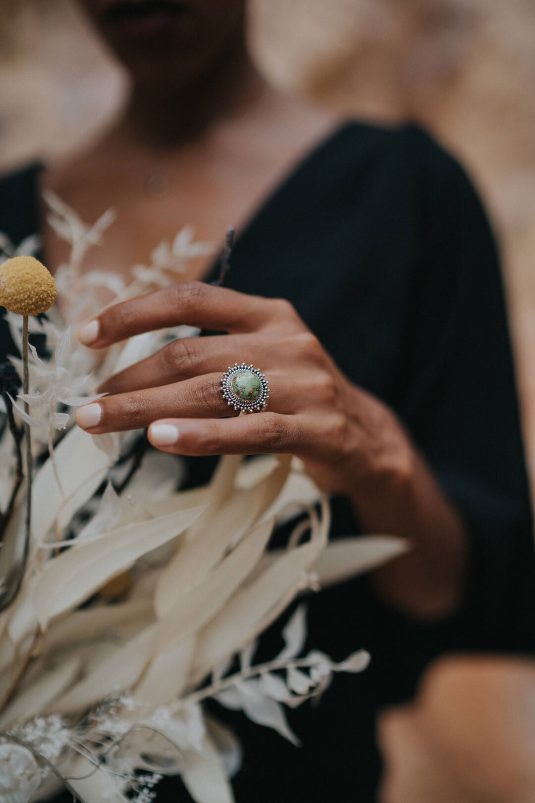 Black woman's hand with diamond ring touching white desert bouquet