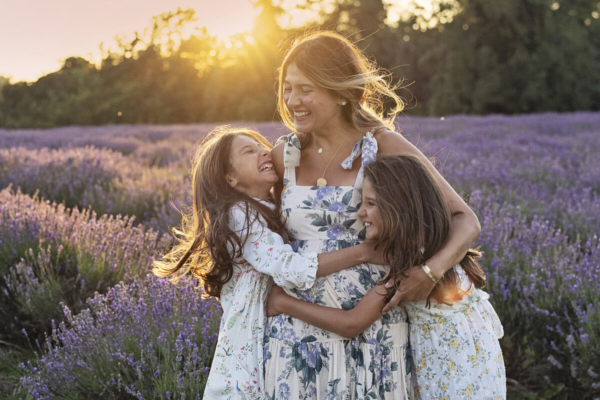 A mother is embraced by her two daughters during a sunset photo shoot in the lavender fields of Surrey, UK