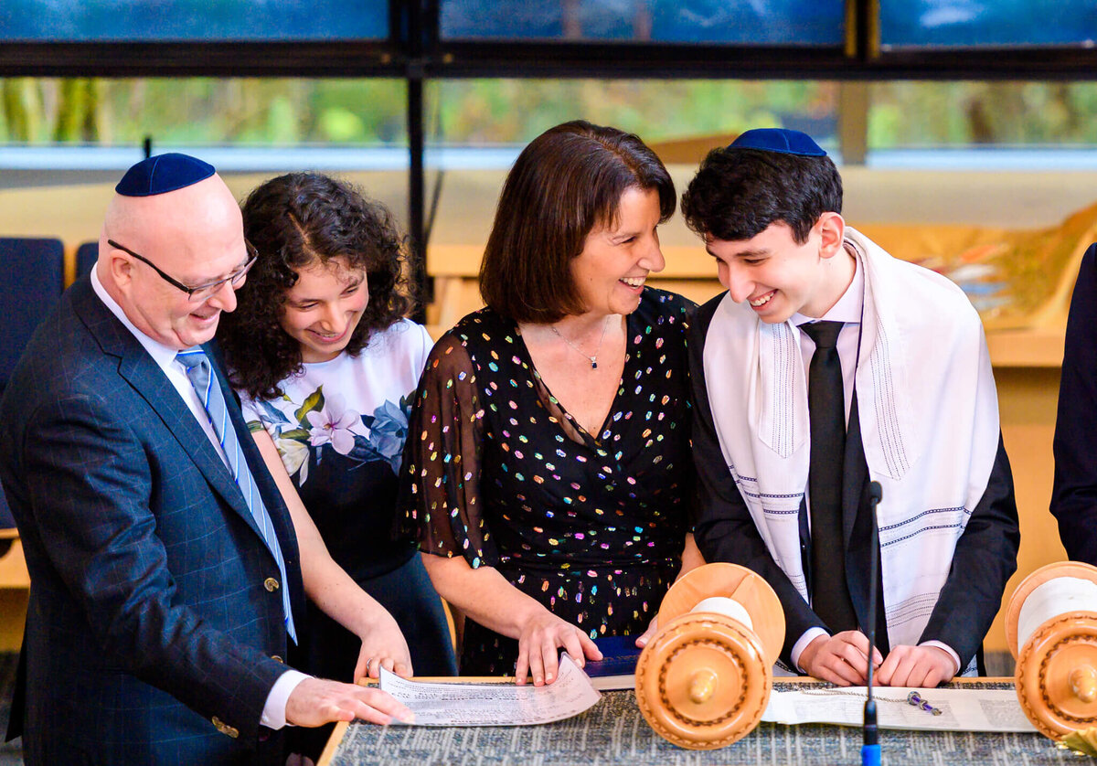 A mother and father laugh with their teenage daughter and son at the altar during his bar mitzvah