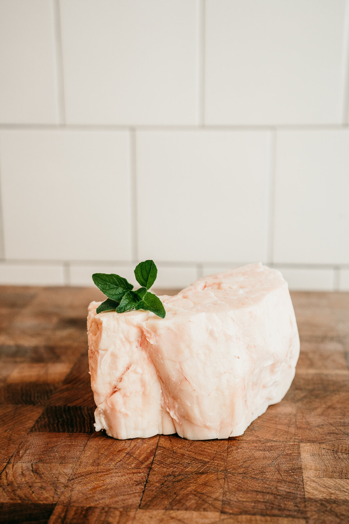 cut of lard against white tiles with green herbs