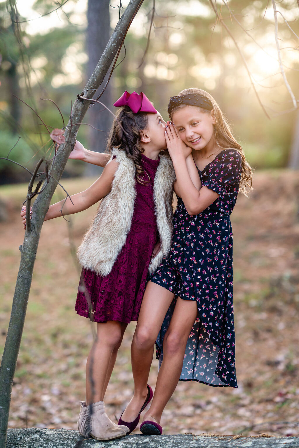Two young sisters are whispering secrets by a tree at Starrs Mill in Fayetteville, GA.