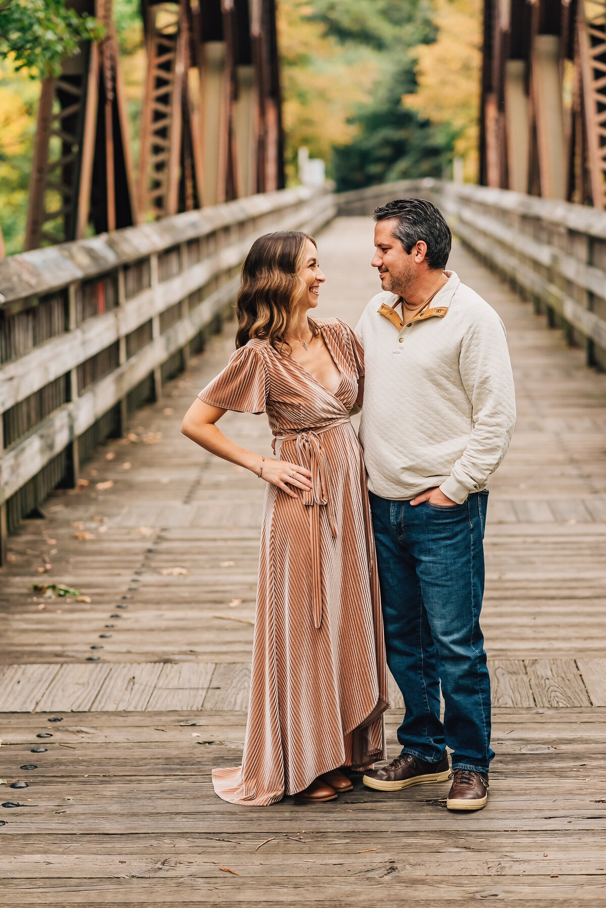 A mom and dad smiling at each other on a bridge at their family session in Canton, Connecticut.