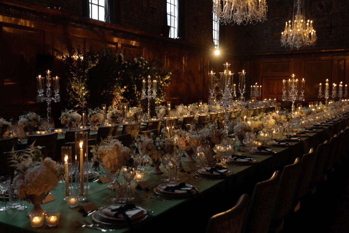 candlelit green and gold wedding dinner design in the ballroom at the ned london with green table linen and glowing candelabras for a chic city wedding