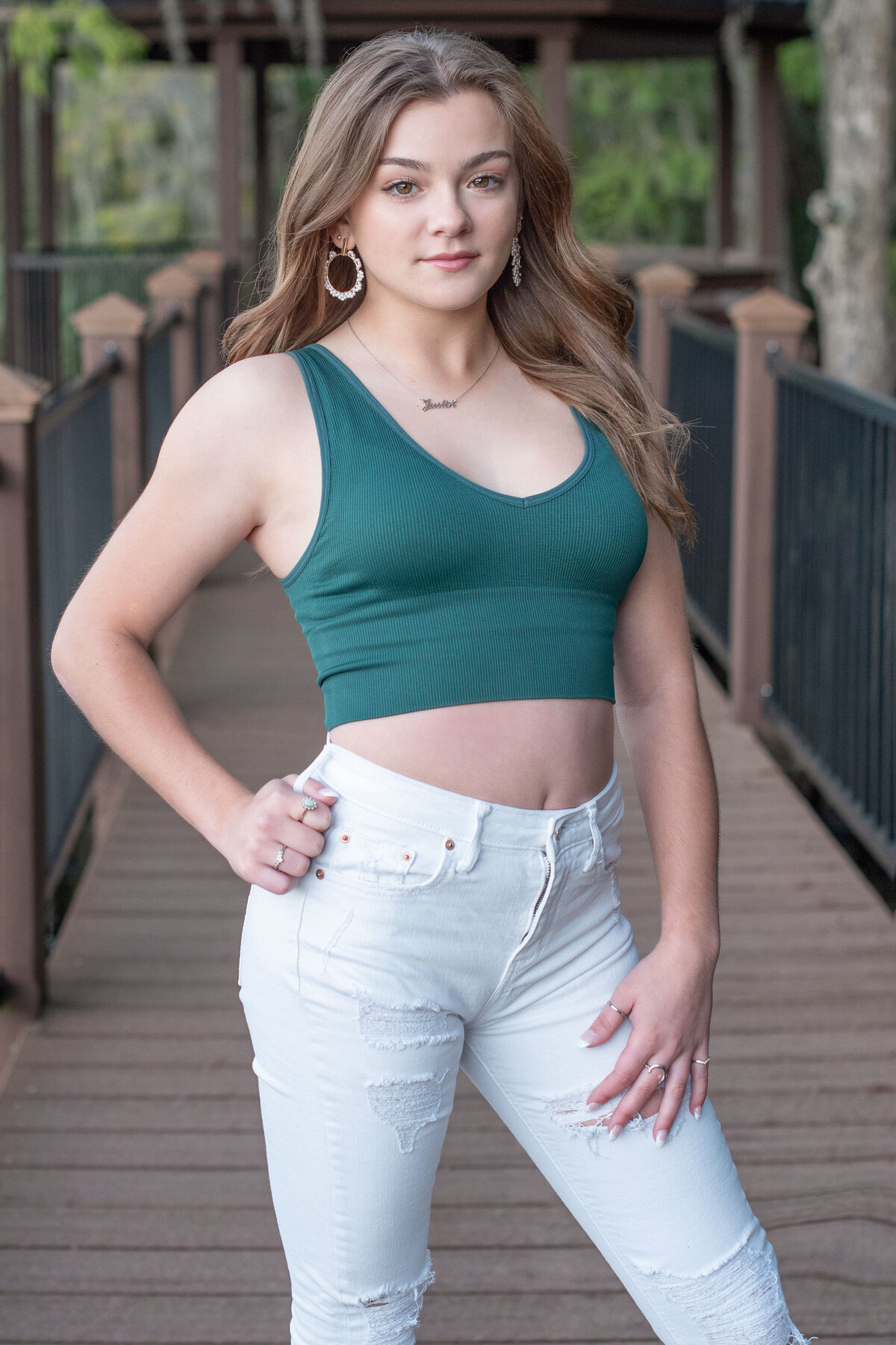 High school senior girl poses on boardwalk in casual clothingl