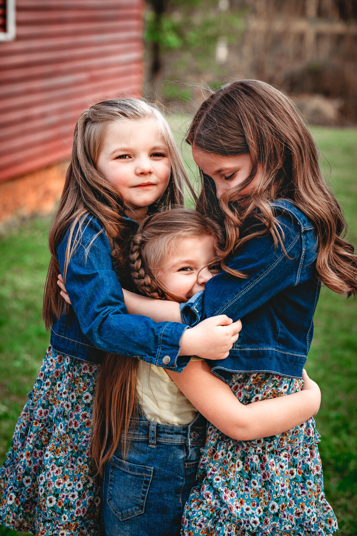 Three young sisters dressed in blue are hugging each other.