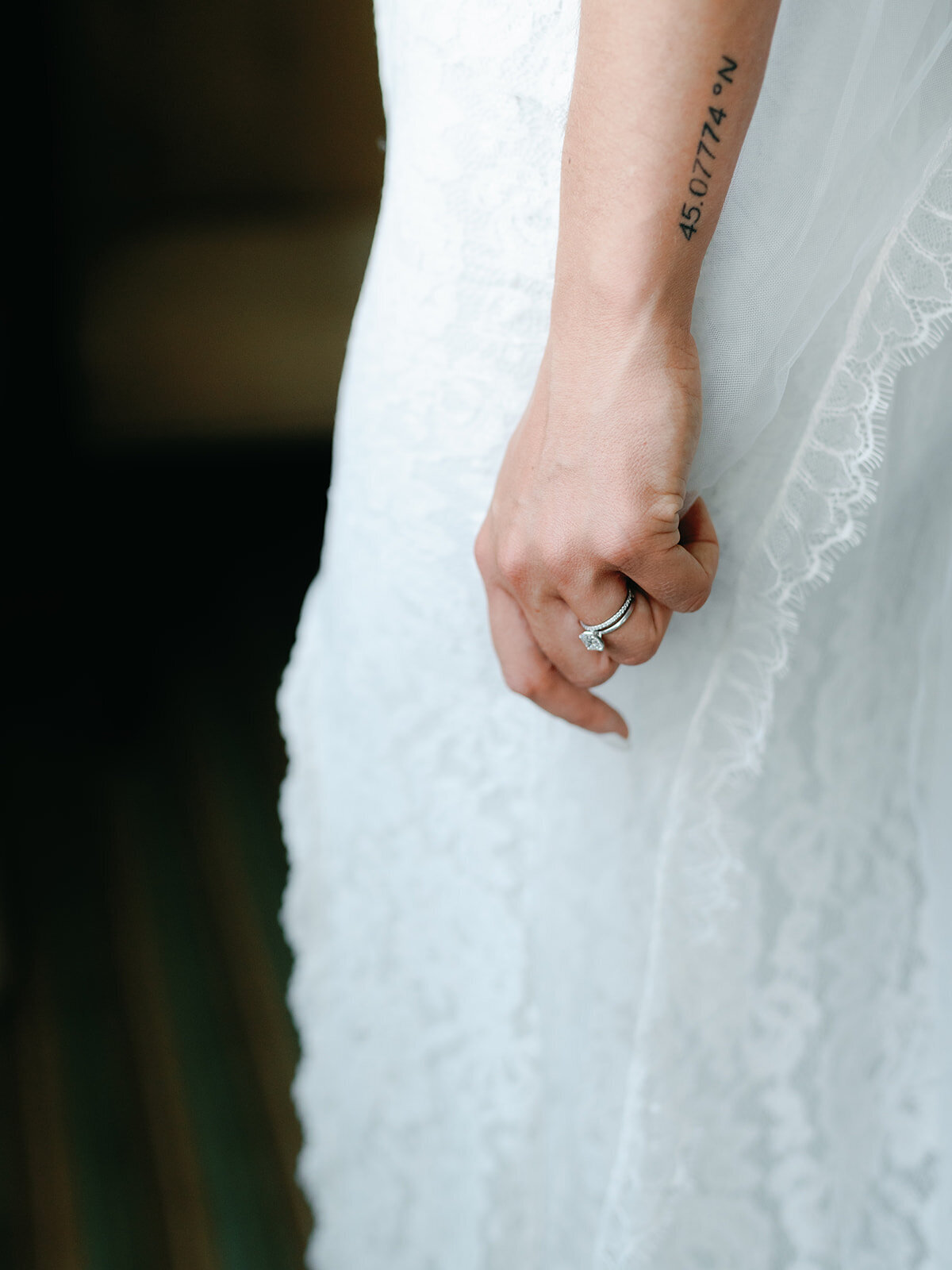 Closeup of brides hand with her ring and the details of her lace wedding dress