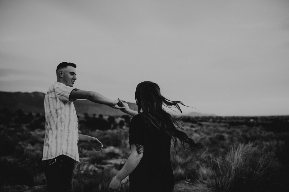 man twirling fiancé in the desert