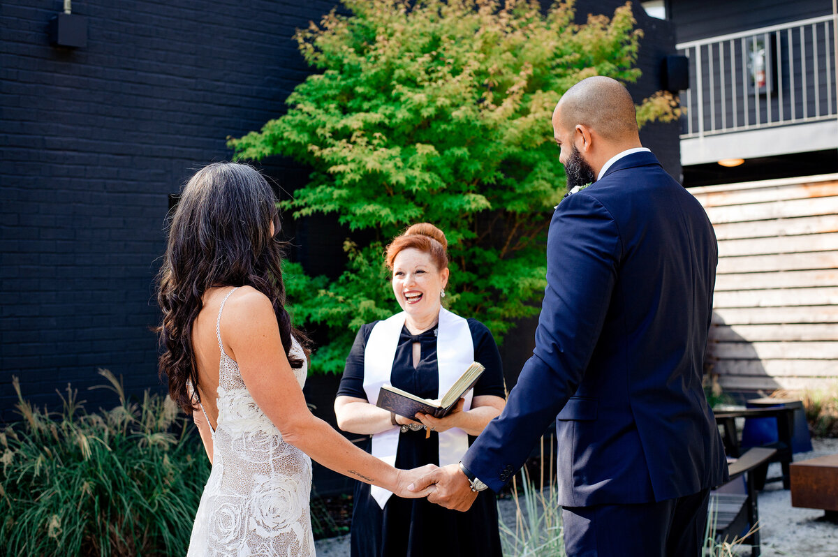 Couple holding hands and laughing with the officiant for their wedding