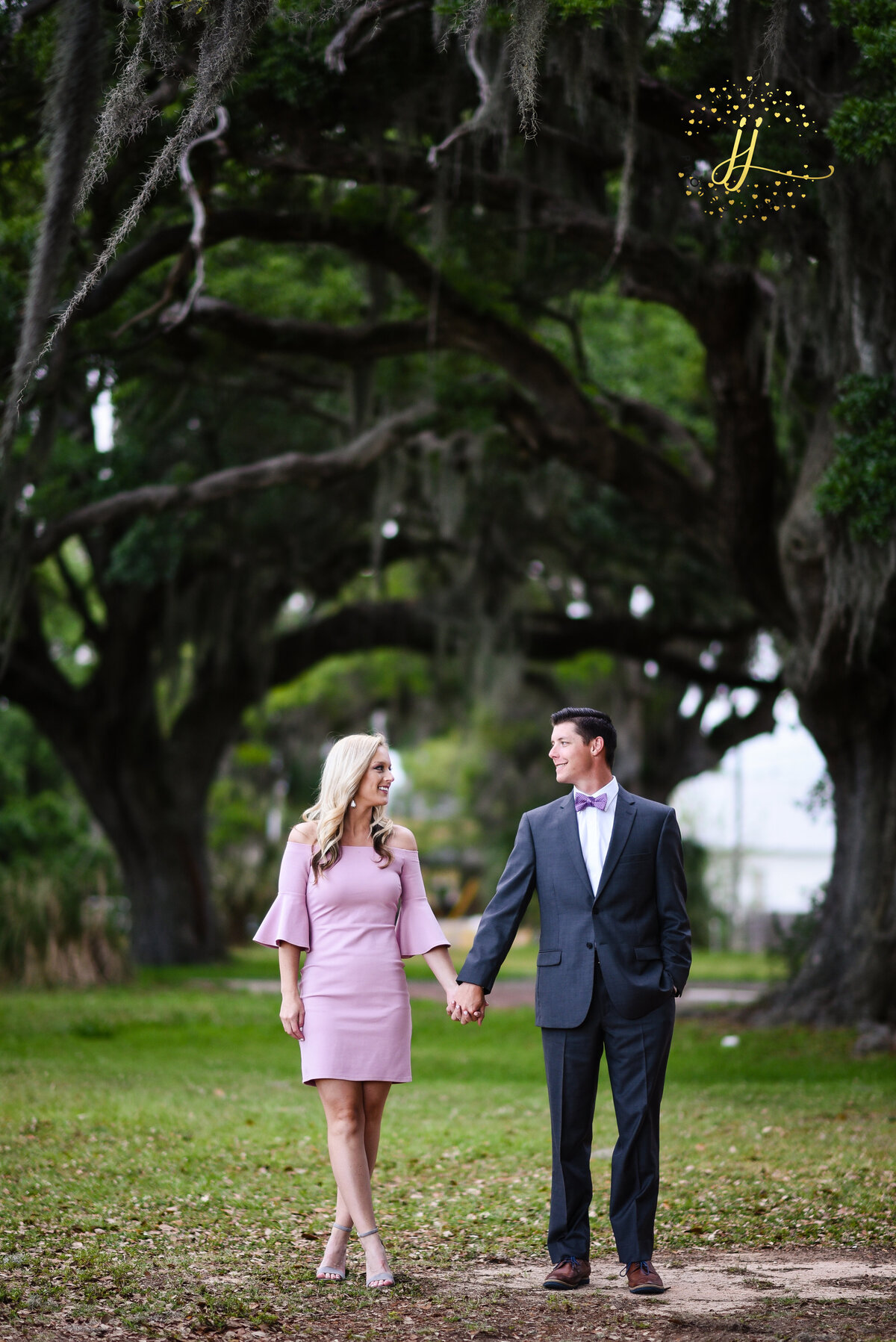 Beautiful Mississippi Engagement Photography: couple walks holding hands under oaks with Spanish Miss in Ocean Springs, MS