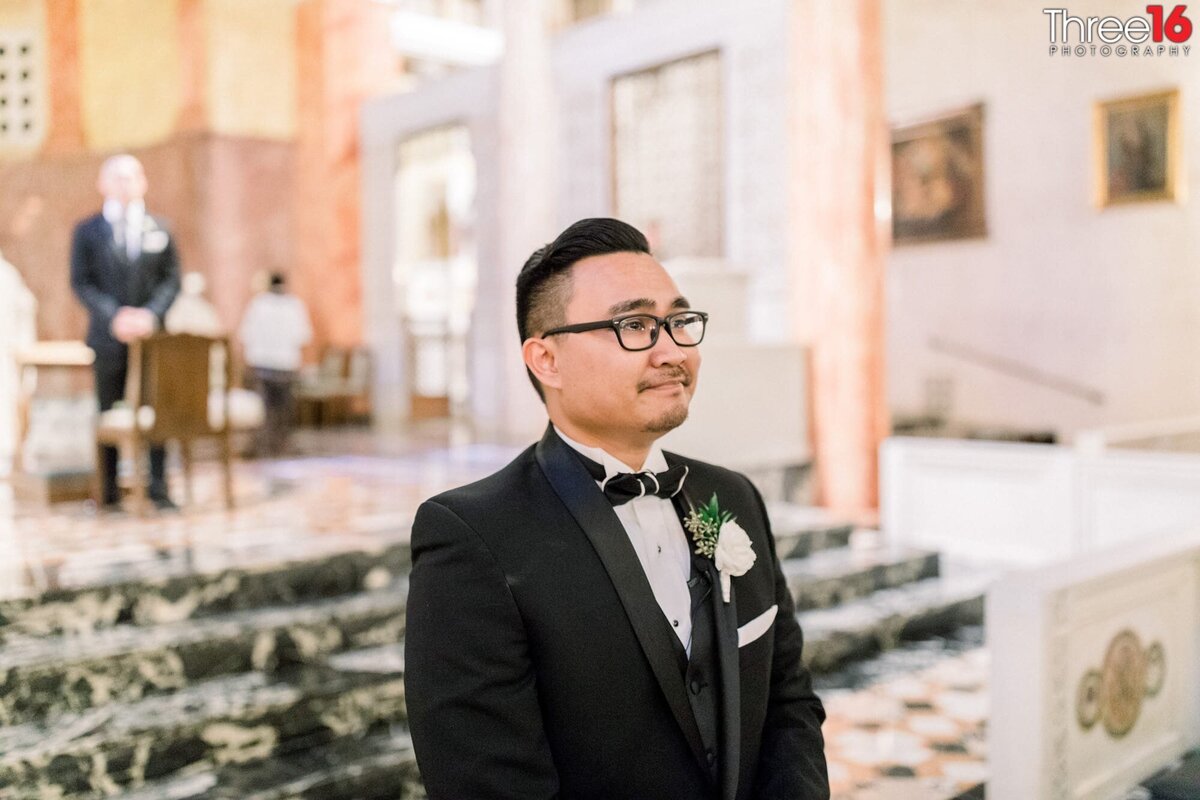 Groom stands at the top of the aisle watching his Bride with his eyes starting to water up