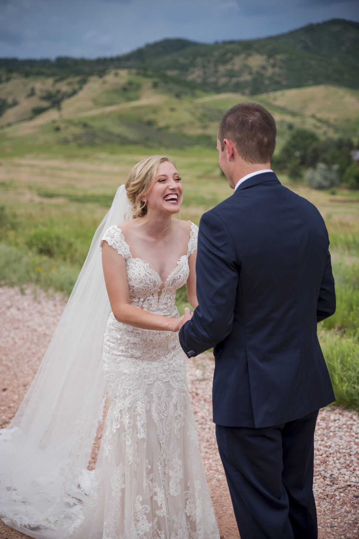 A bride joyfully laughs as she sees her groom during their first look at The Manor House in Littleton, Colorado.