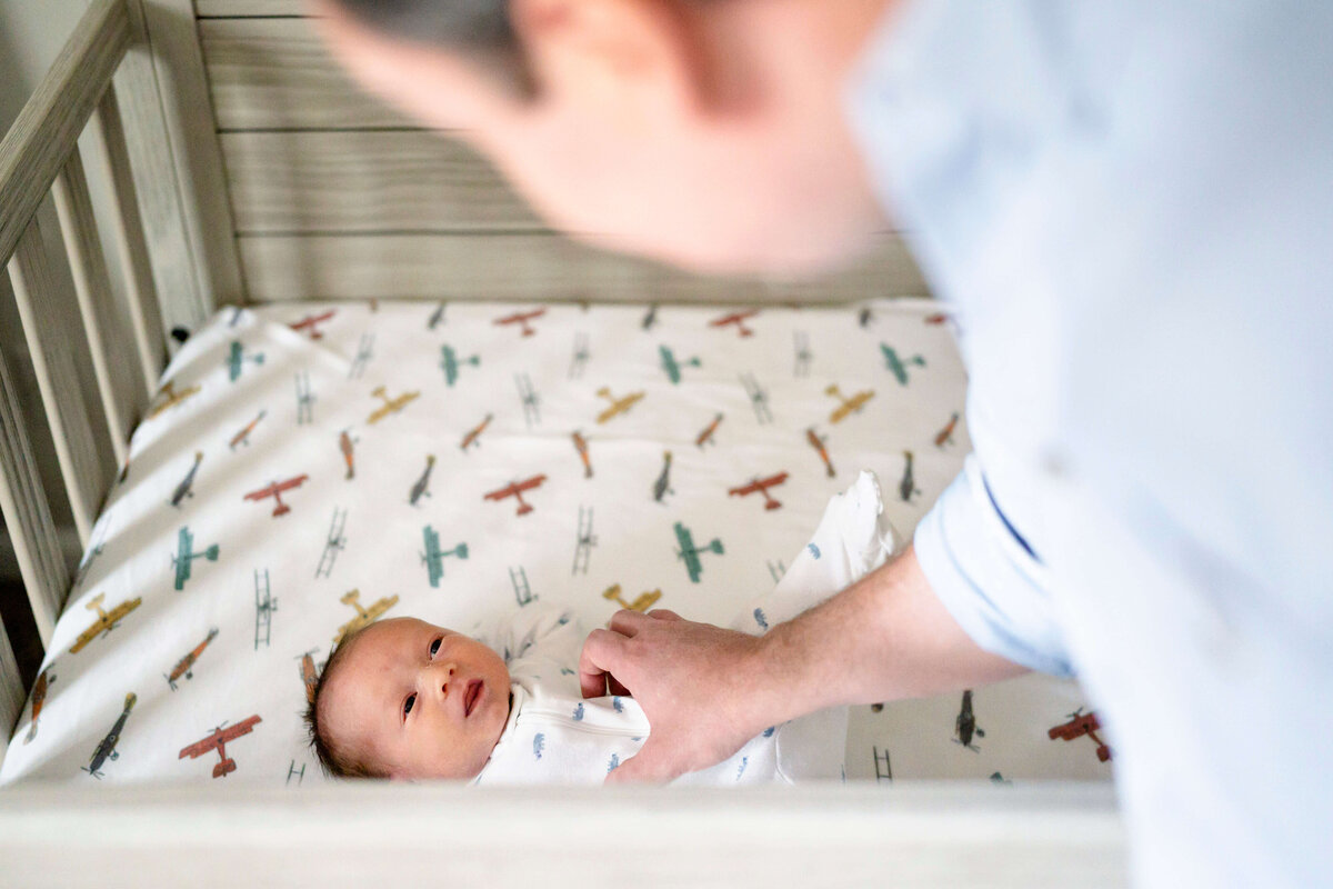 Newborn in crib with father smiling down at him