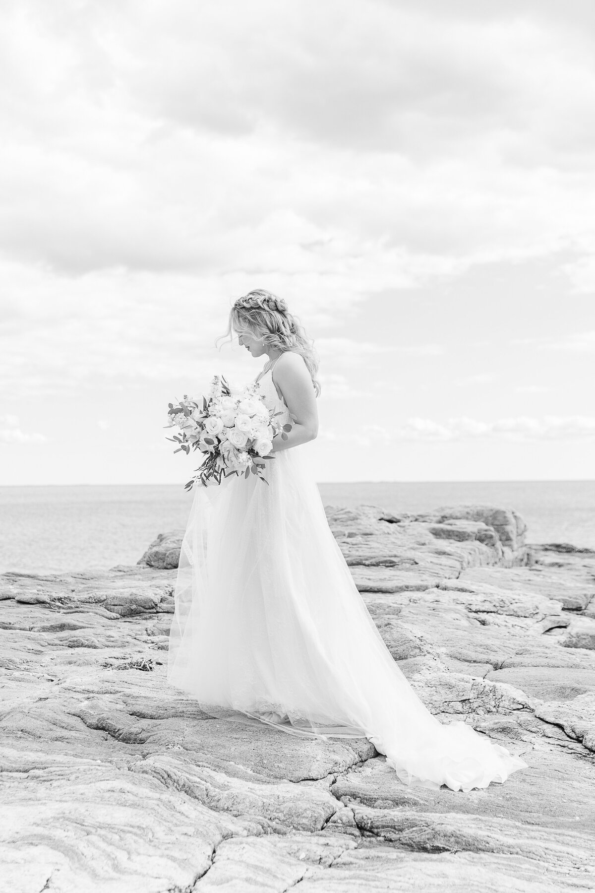 Bride stands on the rocks for a bridal portrait at her Madison Beach Hotel Wedding. Captured by best New England wedding photographer Lia Rose Weddings.