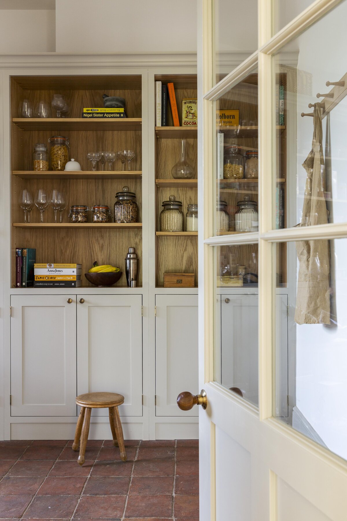 Opening into the pantry with fully stocked shelves and a small antique wooden stool