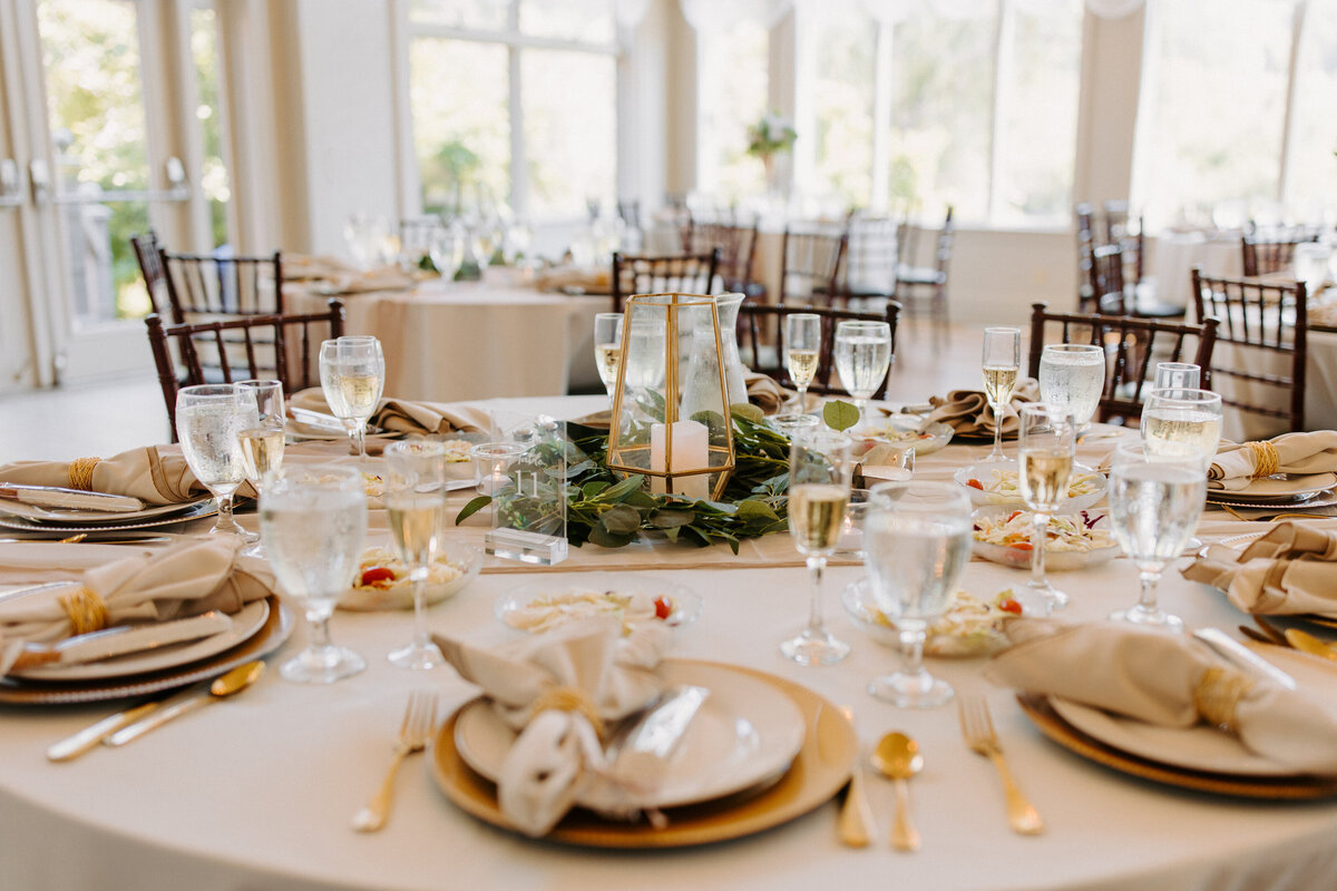 reception table with plates, silverware, napkins and centerpieces on it