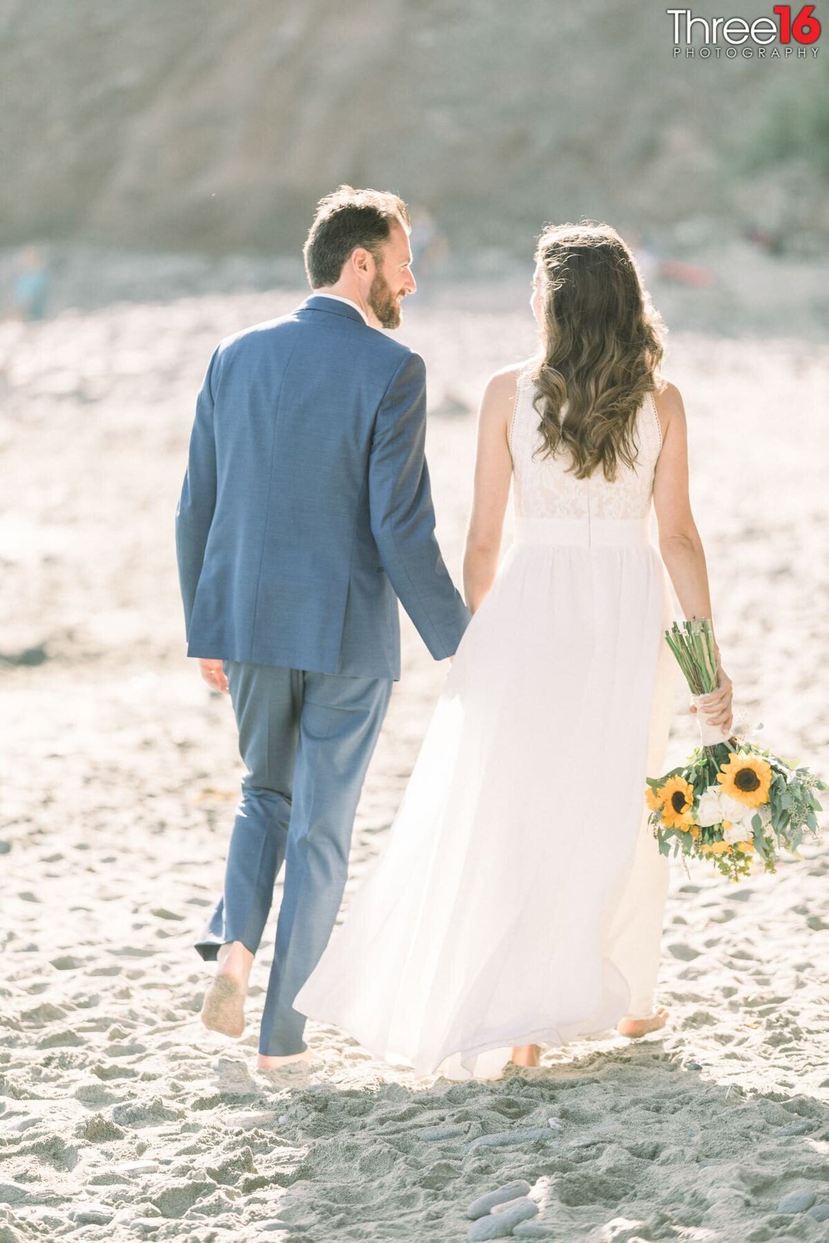 Bride and Groom go for a walk on the beach while holding hands