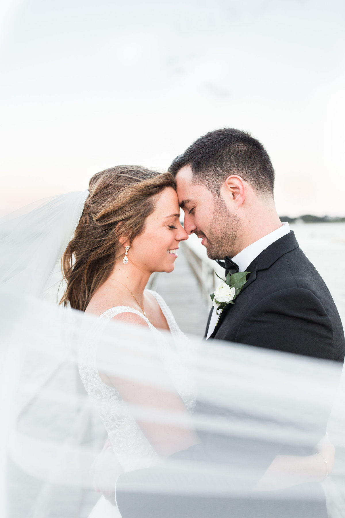 Bride and Groom touching foreheads with windswept veil