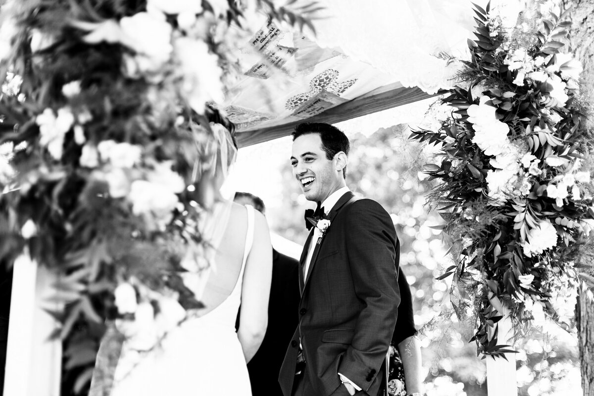 One of the top wedding photos of 2021. Taken by Adore Wedding Photography- Toledo, Ohio Wedding Photographers. This photo is of laughing groom during the ceremony at Cornman Farms